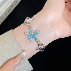 Close-up of a silver starfish and seashell bracelet with turquoise beads on a wrist