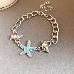Close-up of silver-tone starfish and shell charm chain bracelet with blue studs.