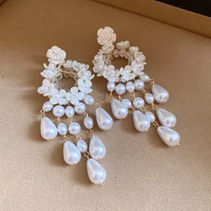 Detailed macro view of French vintage earrings featuring white resin flowers and pearls.