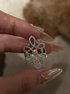Detailed close-up of a vintage hollow flower ring with sparkling zircons on a finger