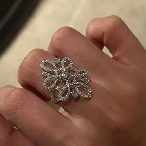 Close-up detail of a vintage-style intricate hollow flower ring with sparkling cubic zirconia stones.
