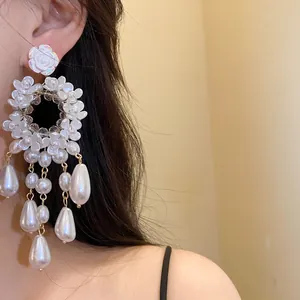 Detail view of French vintage resin flower and pearl drop earrings worn on model