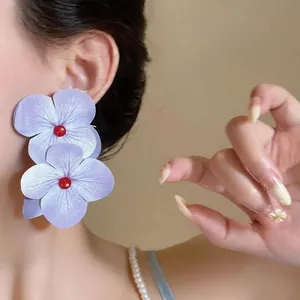 Primer plano detallado de pendientes florales morados de gran tamaño para estilo vacacional