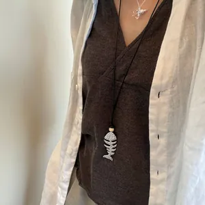 Detail view of a silver vintage fishbone pendant necklace worn over a brown V-neck top