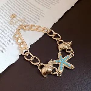 Detailed macro view of gold-toned seashell and turquoise starfish charms on a chain bracelet