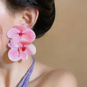 Primer plano de un pendiente de flor rosa grande usado por una modelo