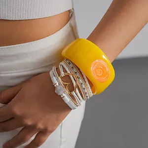 Detail macro view of layered yellow resin bangle and white leather heart bracelet set