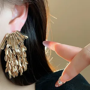 Detailed macro view of luxury gold-tone wheat ear leaf tassel dangle stud earrings