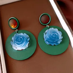 Close-up detail of vintage resin round earrings featuring a blue rose and amber stone accents