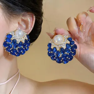 Primo piano di orecchini vintage stile palazzo con perle, pietre blu e cristalli
