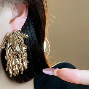Detailed macro shot of elegant gold wheat leaf tassel earrings with layered metallic textures