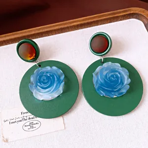 Close-up detail of vintage resin round earrings featuring a blue rose on a green base