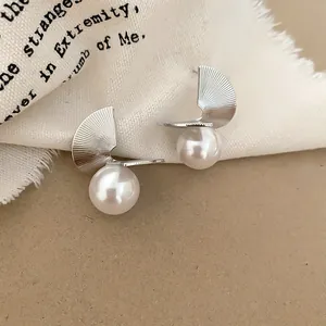 Close-up of French vintage silver spiral fan-shaped earrings with white pearl detail