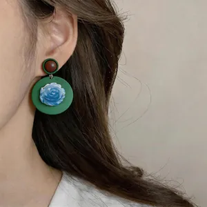 Vintage style resin circular drop earrings with blue flower detail shown on model's ear