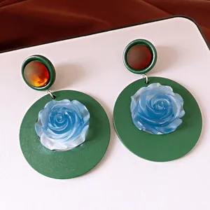 Detailed macro view of vintage green resin earrings featuring a light blue rose flower center