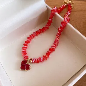 Elegant red crystal beaded necklace with a gold-tone heart pendant in a gift box