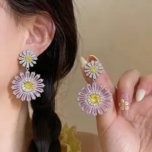Elegant zircon daisy flower drop earrings with pink and yellow stones on ear model.