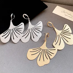 Detail view of gold and silver ginkgo leaf earrings with textured matte finish