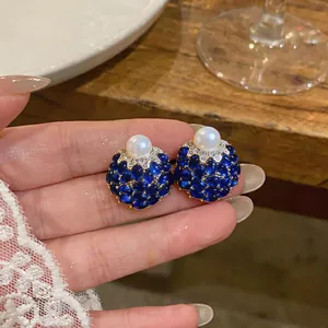 Primo piano di eleganti orecchini a perno vintage con perle e cristalli blu lucidi