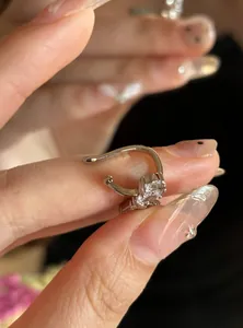 Detailaufnahme eines glitzernden sternförmigen Zirkonia-Ohrclips an einem Finger