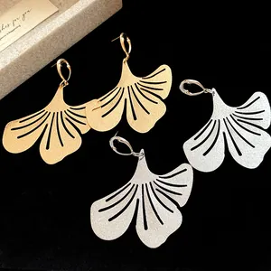 Macro view of elegant gold and silver ginkgo leaf shaped drop earrings for women