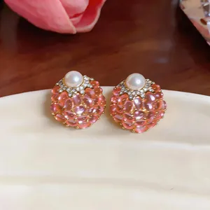 Primo piano di orecchini vintage a forma di bacca rosa con perla centrale e cristalli
