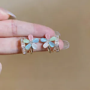 Close-up detail of silver-needle flower earrings featuring cat eye stones and zircon