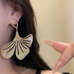 Close-up of gold pleated leaf earring showing intricate metallic texture details