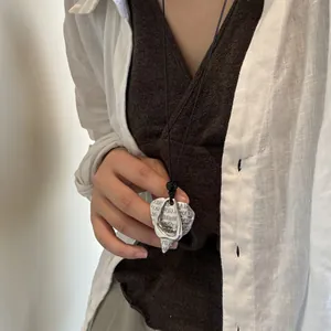Detail view of vintage silver heart-shaped pendant on long necklace worn by a model