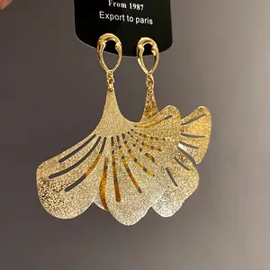 Detailed view of gold-plated ginkgo leaf earrings with frosted texture and cutouts.