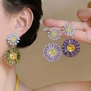 Detail view of crystal daisy drop earrings in green, light purple, and dark purple