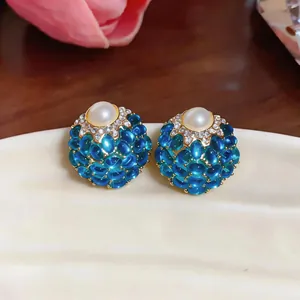 Primo piano di orecchini vintage stile palazzo con perle blu e una perla centrale.