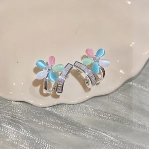 Close-up detail of silver flower earrings featuring colorful cat's eye and zircon stones