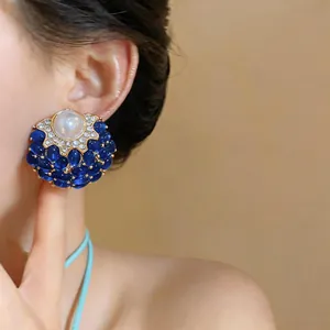 Primo piano di orecchini vintage in stile corte con pietre blu e dettagli in perla.