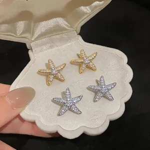 Detailed view of gold and silver starfish stud earrings with sparkling cubic zirconia stones.