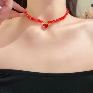 Macro view of a vibrant red beaded necklace with a heart-shaped crystal pendant
