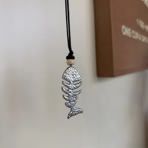 Close-up of vintage silver fishbone pendant with bead on black cord necklace
