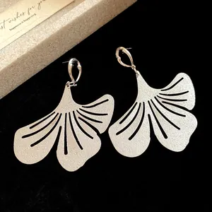 Close-up detail of matte silver ginkgo leaf drop earrings displayed on black velvet background