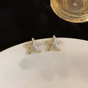 Detailed macro view of elegant gold-plated starfish stud earrings with pavé zircons