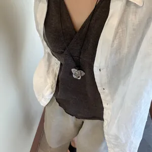 Vintage silver flower pendant necklace on long black cord paired with a linen shirt
