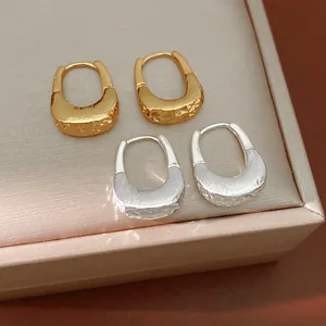 Dettaglio orecchini a cerchio a U placcati oro 18 carati e argento con texture.