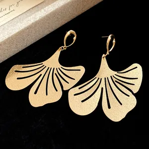Close-up of gold metal ginkgo leaf drop earrings with sandblasted texture details