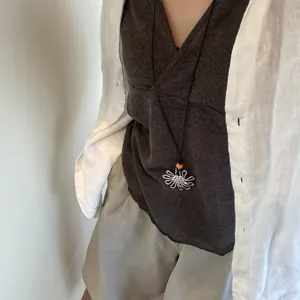 Detail view of a retro silver flower pendant necklace worn with casual linen outfit