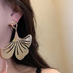 Detailed view of an elegant gold ginkgo leaf dangle earring worn on the ear for a vintage look