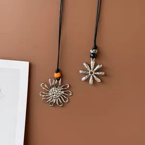 Detail showing two silver retro flower pendants on black cord with decorative beads