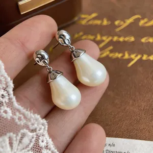 Close-up of elegant pear-shaped pearl earrings with silver molten texture details