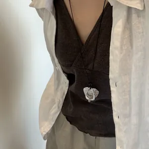 Macro view of a vintage silver pendant necklace worn over a stylish brown V-neck top