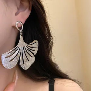 Close-up of silver ginkgo leaf earring featuring a textured metallic finish and hollow design.