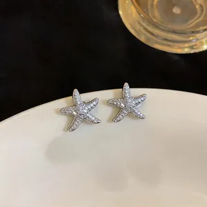 Detailed close-up of elegant sparkling zircon starfish stud earrings on a ceramic plate