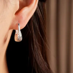 Dettaglio di un orecchino a cerchio a U in argento minimalista con trama stropicciata